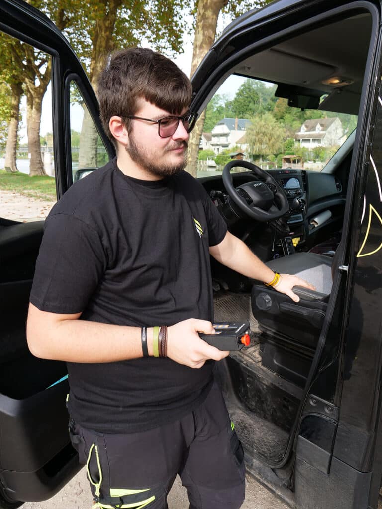 Personne tenant une télécommande, debout près d'une voiture.