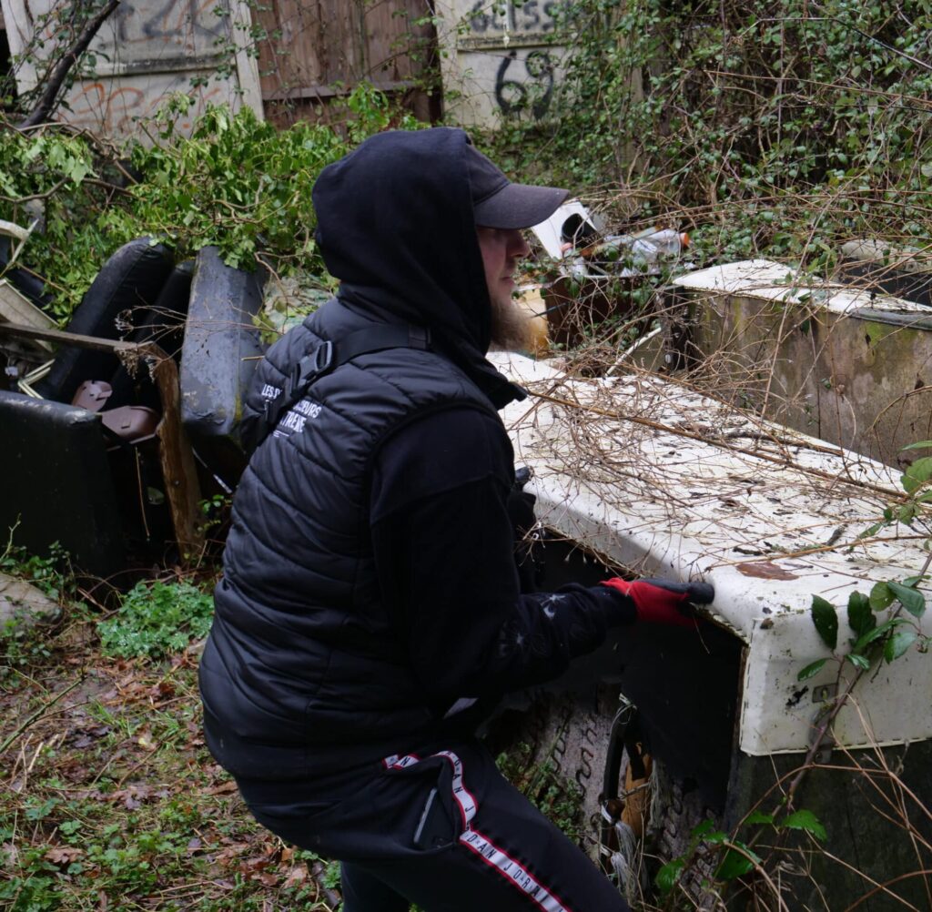 Personne dégageant un piano abandonné dans la nature.