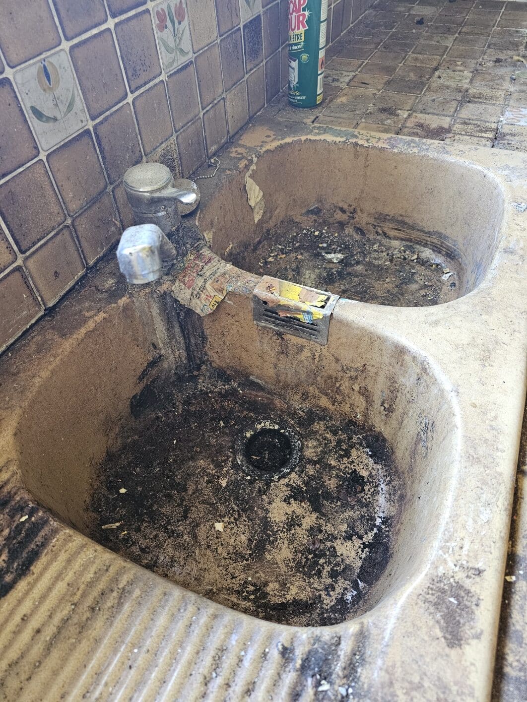 Évier double très sale avec taches et résidus.