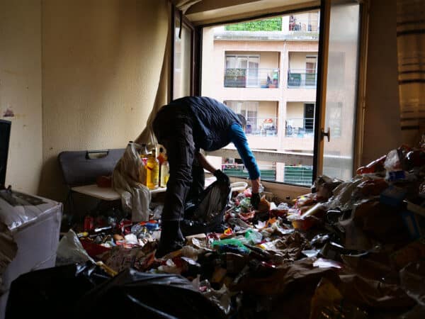 Personne nettoyant une pièce encombrée de déchets.