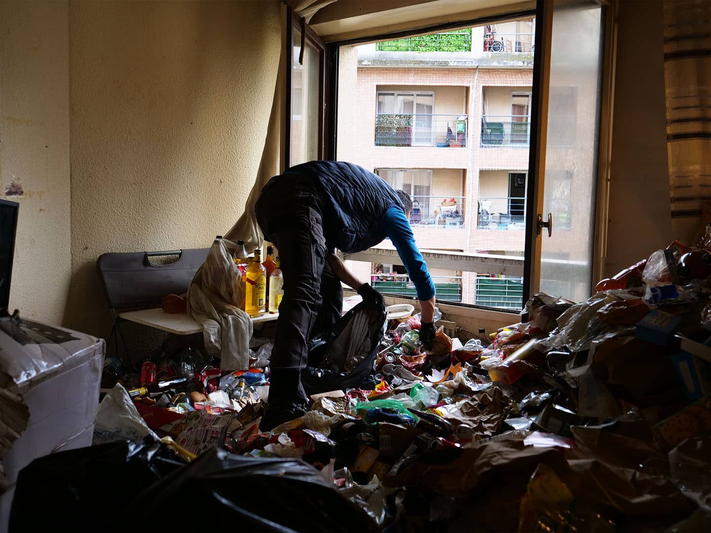 Personne nettoyant une pièce encombrée de déchets.
